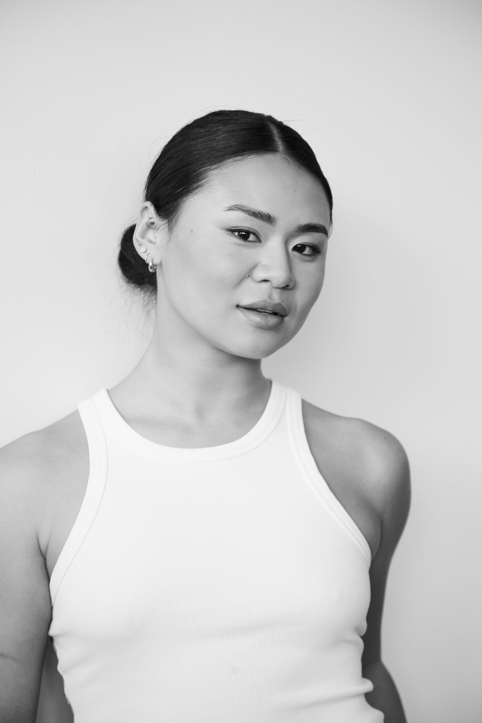 Woman in a white tank top against a plain background.