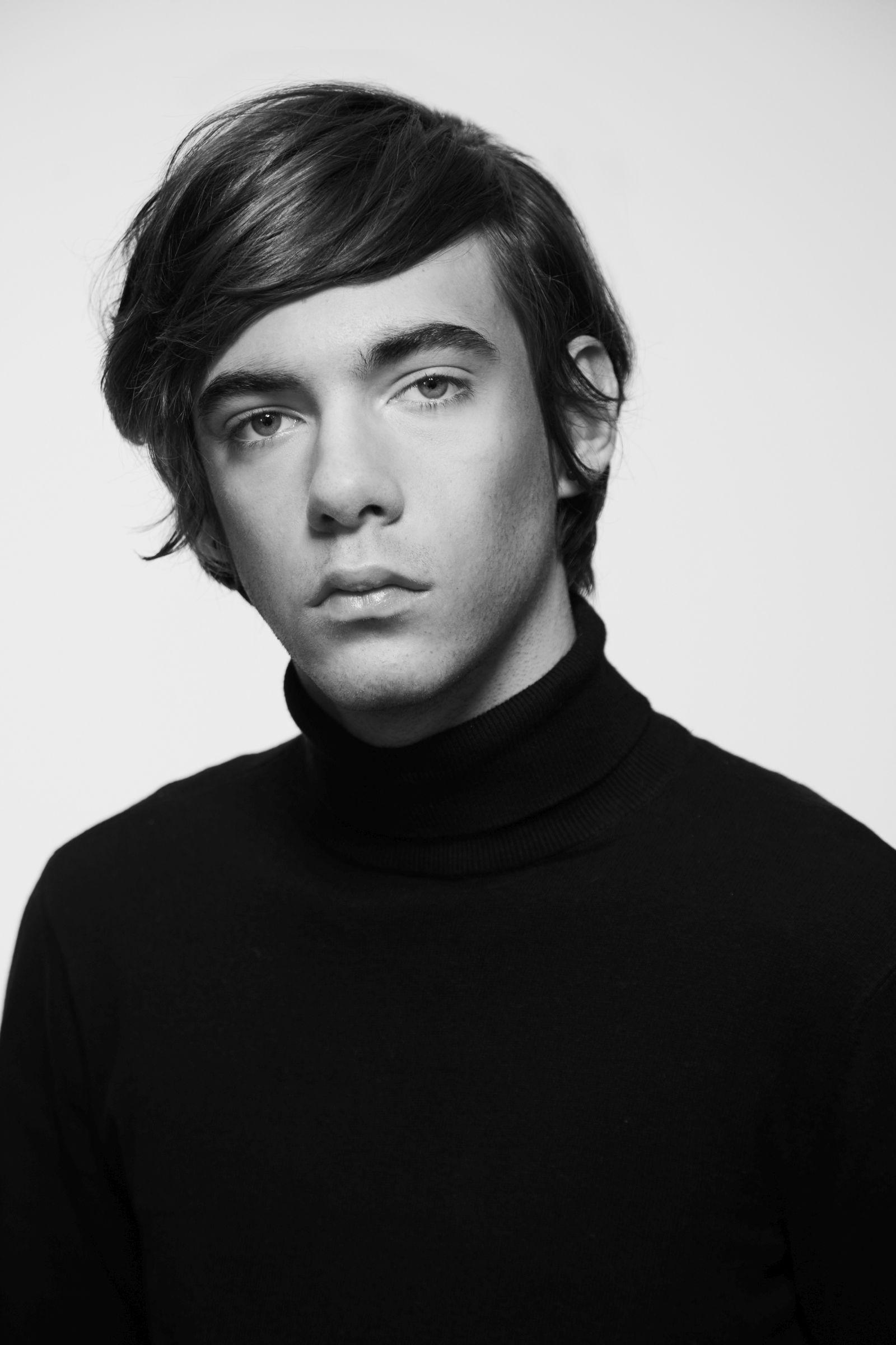 Black-and-white studio headshot, person with side-swept hair in black turtleneck, neutral gaze.