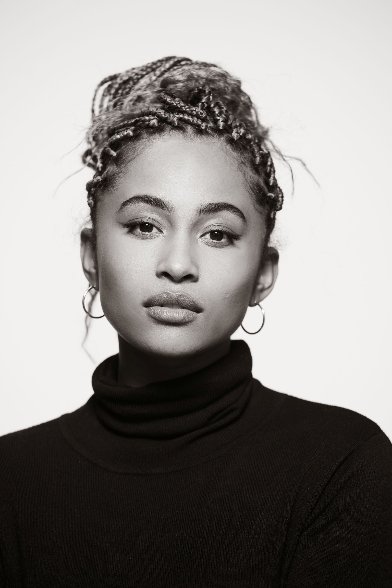 Black and white portrait of a woman in a turtleneck, hair in braids.