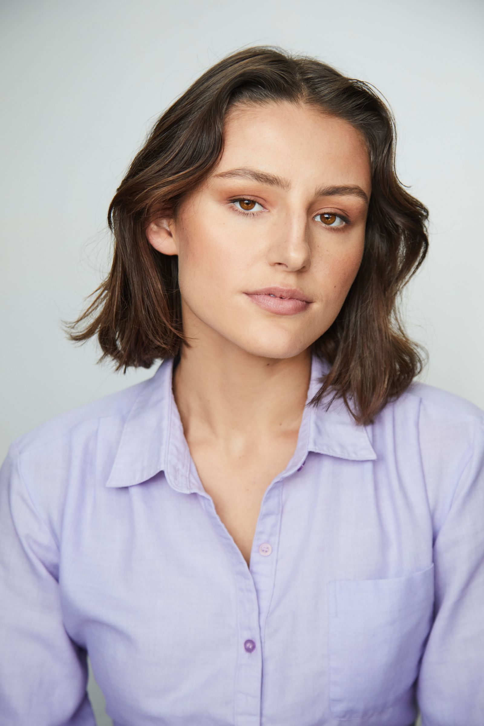 Person with short brown hair in a light purple shirt.