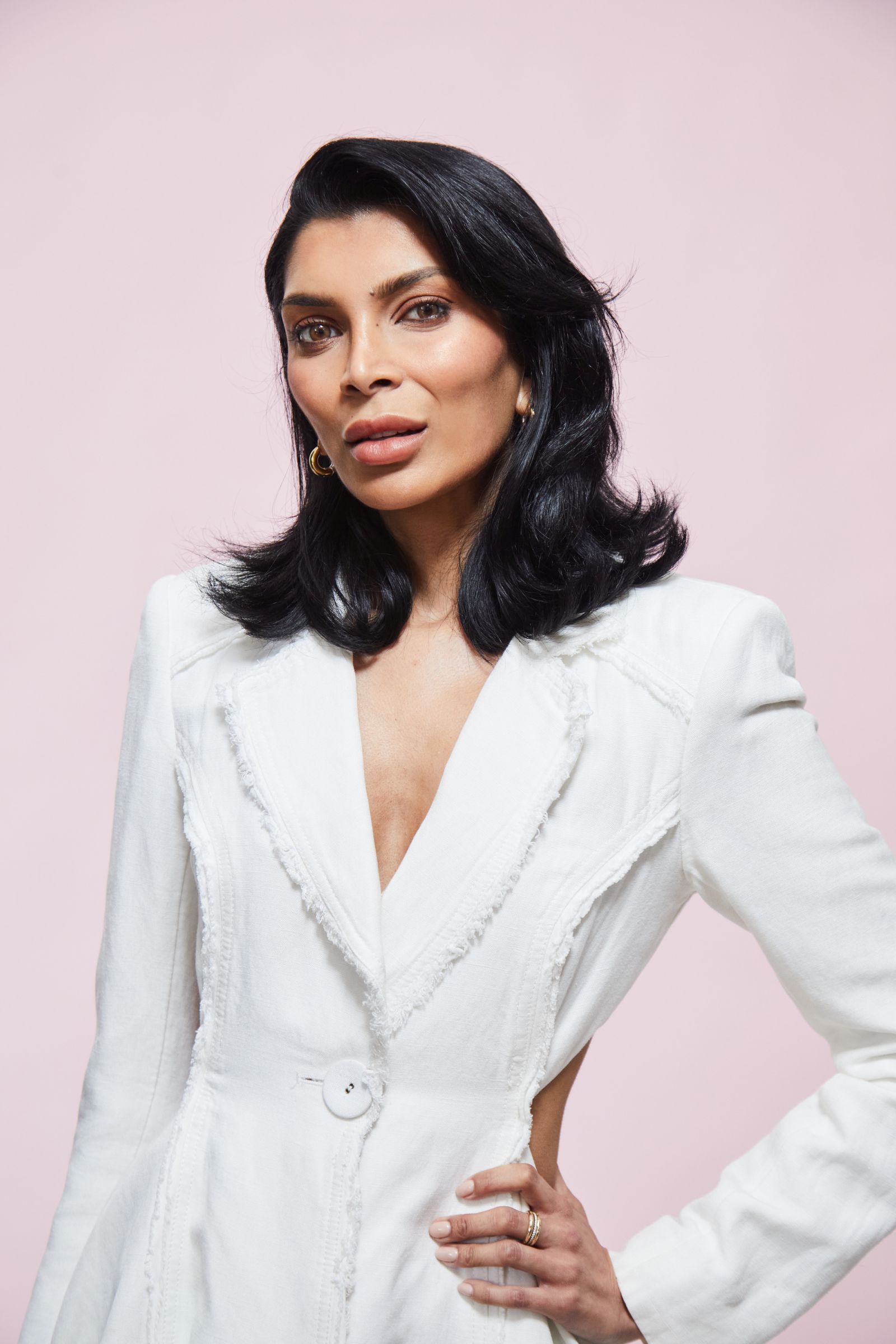 Person in a white jacket against a soft pink background.