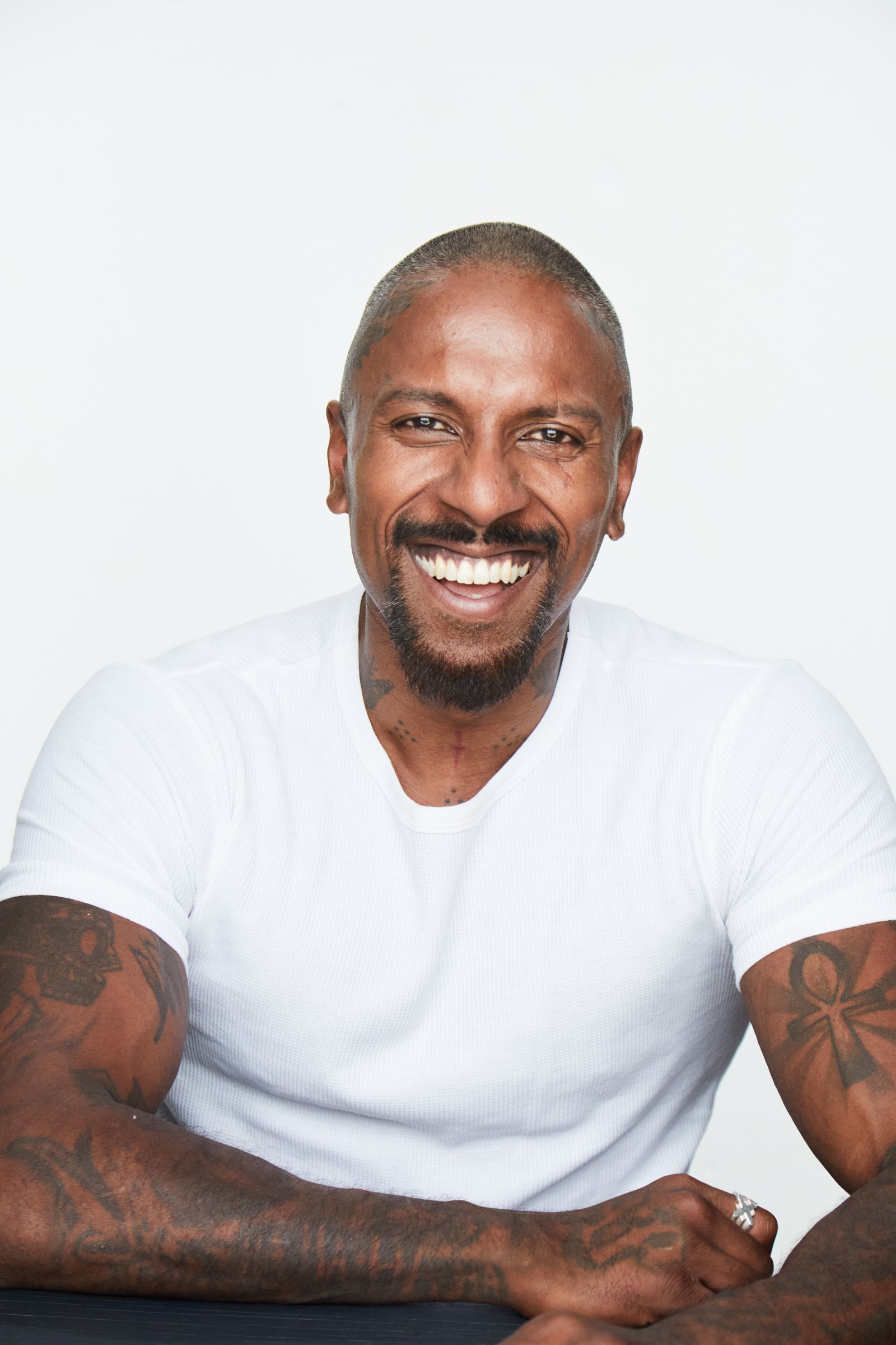 Man with a big smile in white shirt against plain background.