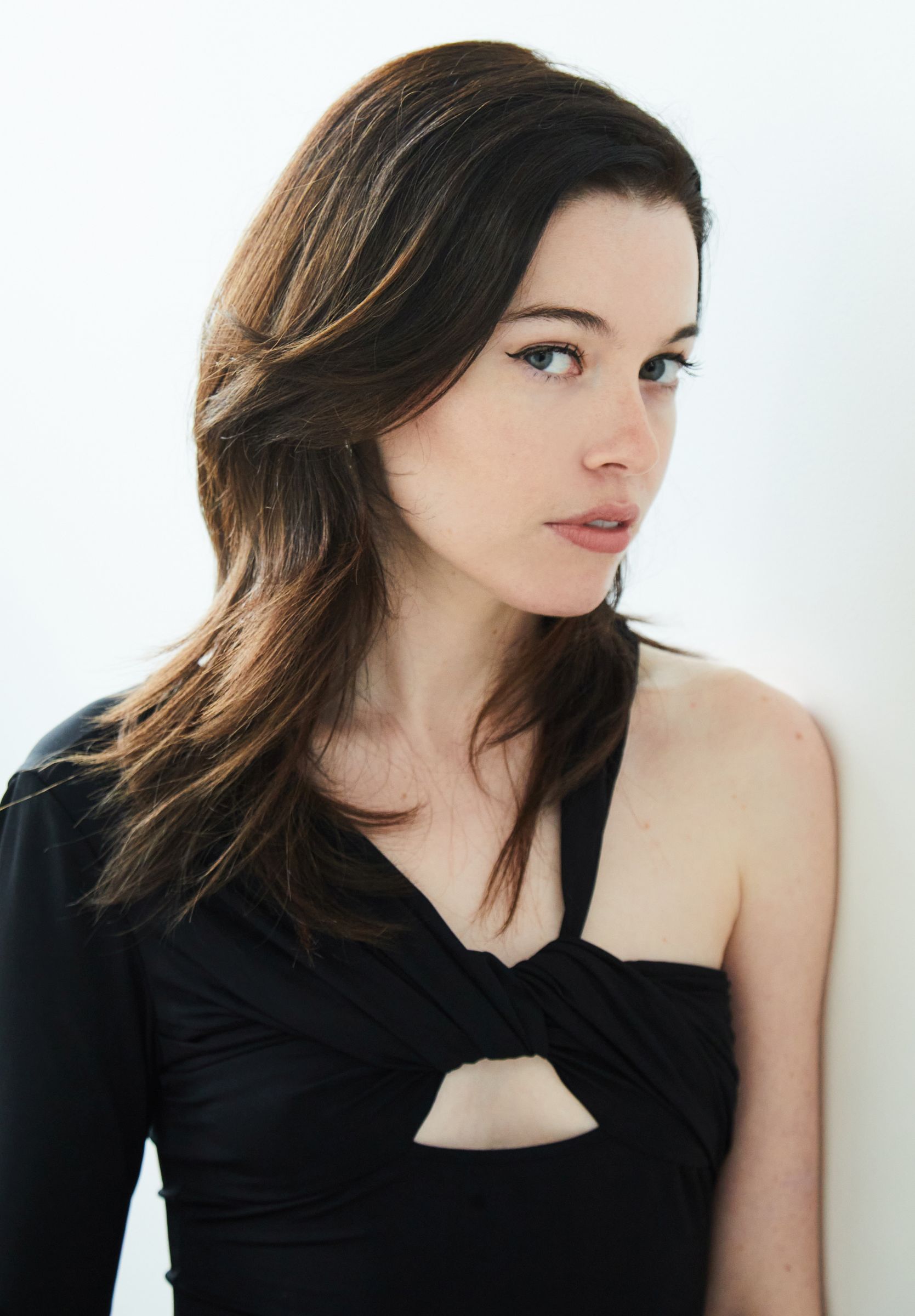 Person with long dark hair and a black outfit against a white background.