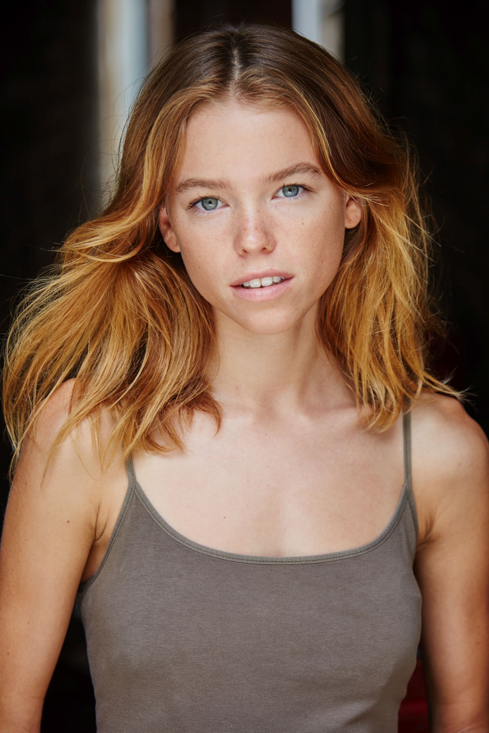 Person with long hair wearing a gray tank top, facing forward.